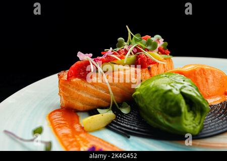 Filet de saumon aux tomates confites et asperges vertes aux spaghetti noirs, sauce pesto et sorbet carottes et fruits de la passion Banque D'Images