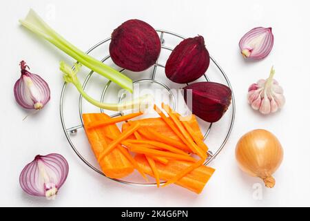 Carottes, betteraves, oignons et tiges de céleri tranchés : la nourriture reste vie. Pose à plat. Arrière-plan blanc. Banque D'Images