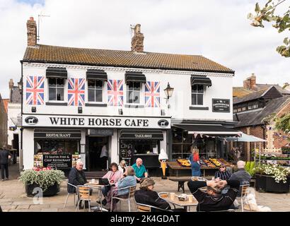 Personnes assises à l'extérieur du café White Horse à Thirsk Market place, North Yorkshire, Angleterre, Royaume-Uni Banque D'Images