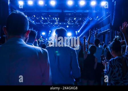 Goias, Brésil – 25 septembre 2022 : détail de l'audience d'un spectacle de théâtre éclairé par diverses lumières colorées. Banque D'Images