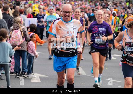 Londres, Royaume-Uni, 2nd octobre 2022. Plus de 40 000 participants s'emprennent dans les rues de la capitale pour le Marathon de Londres 42nd. L'événement qui attire des coureurs d'élite et des athlètes en fauteuil roulant permet également de relever des millions de livres pour la charité grâce à la participation de coureurs de club et de fitness ainsi que ceux qui veulent juste relever le défi de 26 miles. Un homme mature qui appuie l'organisme de bienfaisance Alzheimer's Research. Banque D'Images