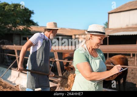 Femme mature près d'un enclos avec des vaches à la ferme Banque D'Images