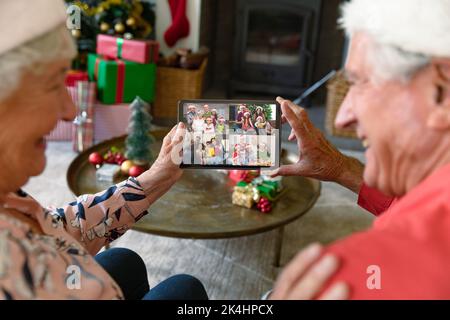 Un couple caucasien senior à santa Hats sur la tablette de noël appel vidéo avec la famille. noël, fête et technologie de communication. Banque D'Images