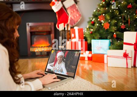 Redhead woman lying on floor using laptop à Noël à la maison dans le salon Banque D'Images
