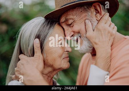 Portrait d'un couple aîné amoureux, debout à l'extérieur dans la nature. Banque D'Images