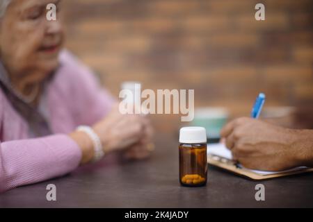 Gros plan de la femme âgée prenant des pilules par le soignant. Banque D'Images
