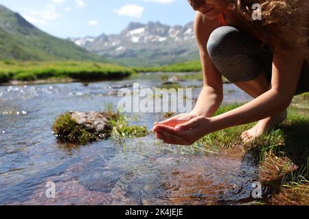 Gros plan d'un yogi qui se fait tremper les mains et qui attrape l'eau de la rivière dans la montagne Banque D'Images