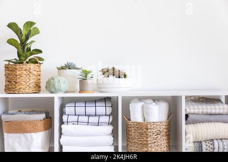 Plantes en pots dans des paniers de paille écologique sur la tablette de linge de lit armoire de rangement textile Banque D'Images