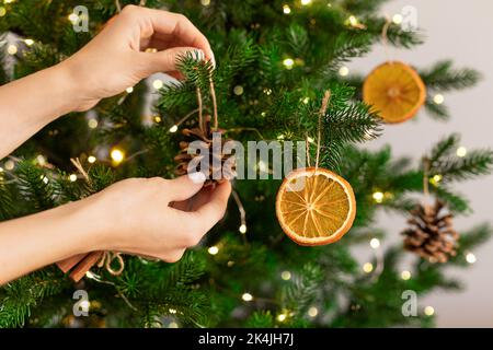Les mains des femmes pendent une décoration faite à la main sur un arbre de Noël. Banque D'Images