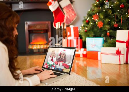 Redhead woman lying on floor using laptop à Noël à la maison dans le salon Banque D'Images
