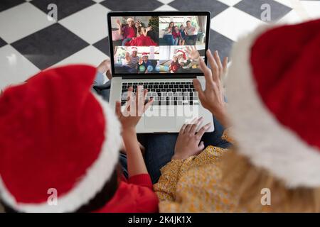 La mère et la fille agaiseront pour passer un appel vidéo de noël avec leur ordinateur portable et leurs amis. noël, fête et technologie de communication. Banque D'Images