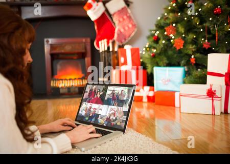 Redhead woman lying on floor using laptop à Noël à la maison dans le salon Banque D'Images