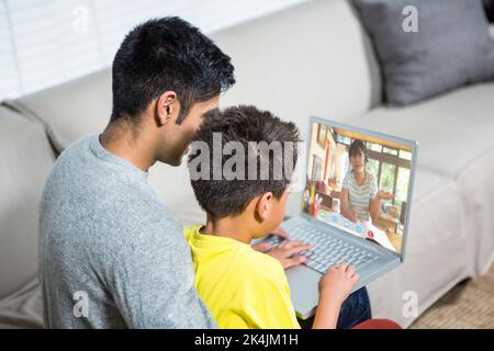 Père et fils utilisant un ordinateur portable sur le canapé dans la salle de séjour Banque D'Images