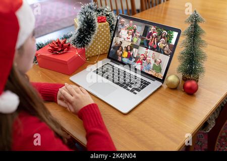 Femme caucasienne dans le chapeau de santa faisant noël portable appel vidéo avec divers amis et la famille. noël, festivité et la technologie de communication. Banque D'Images