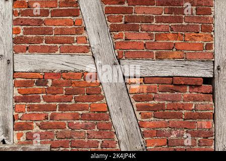 Texture de fond d'un vieux mur de cadre en bois, composé de poutres en bois altérées et de briques de pierre à bakestone rouges, typique pour l'architecture à colombages Banque D'Images