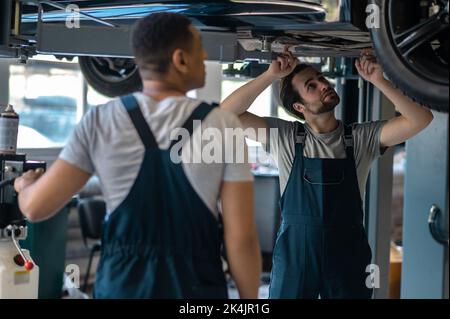 Les travailleurs de l'atelier de réparation automobile qui examinent la voiture du client Banque D'Images