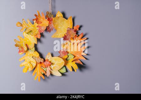 Couronne en papier jaune-rouge d'automne maison sur fond de mur gris. Bricolage saisonnier Banque D'Images