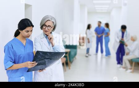 Infirmière avec une femme radiologue regardant l'IRM du cerveau, debout dans le couloir de l'hôpital pendant la journée de travail. Établissement de soins de santé Banque D'Images