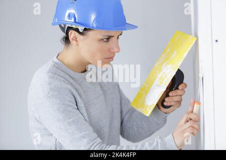 femme travaillant plâtrant les murs de peinture à l'intérieur de la maison Banque D'Images