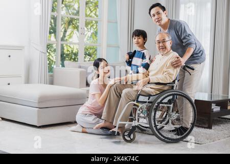 Bonne famille asiatique de personnes âgées avec belle fille, son mari et petit-fils prennent soin de vieux homme assis sur un fauteuil roulant dans la maison, papa positif ont str Banque D'Images