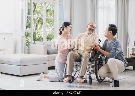 Bonne famille asiatique de personnes âgées avec belle fille, son mari et petit-fils prennent soin de vieux homme assis sur un fauteuil roulant dans la maison, papa positif ont str Banque D'Images