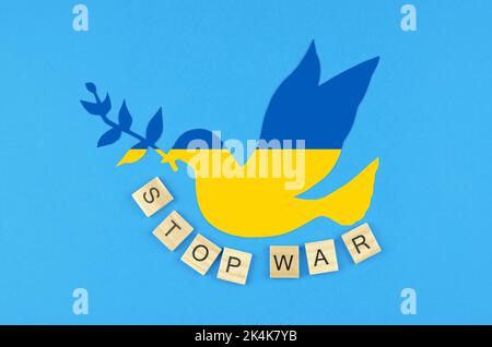 Colombe de la paix dans les couleurs du drapeau de l'Ukraine et l'inscription arrêtent la guerre sur un fond bleu Banque D'Images