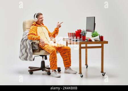Jeune homme en costume incroyable assis au bureau d'ordinateur à la maison. Art, idées, créativité, travail et concept de vacances Banque D'Images