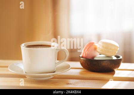 Petit déjeuner confortable avec une tasse de café et des macarons sur une table rustique en bois. Banque D'Images