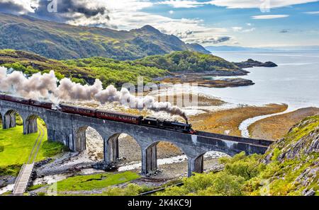 TRAIN DE VAPEUR JACOBITE LONG PANACHE DE FUMÉE SOMBRE DU MOTEUR LORSQU'IL TRAVERSE LE VIADUC LOCH NAN UAMH Banque D'Images