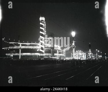 1955, historique, de soirée et une vue sur le nord de l'Angleterre Blackpool illuminations, montrant les gens à l'extérieur de la plage de plaisir et casino, Blackpool, Angleterre, Royaume-Uni. Banque D'Images