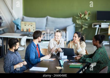 Jeunes collègues à l'écoute d'un homme d'affaires confiant expliquant son point de vue ou son idée d'un nouveau projet lors d'une réunion de travail Banque D'Images
