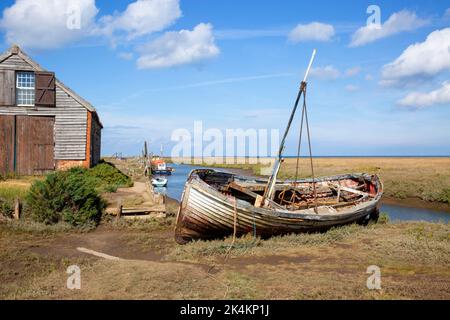 Grange à charbon et bateau sur l'ancien port et l'estuaire à marée à Thornham, sur la côte nord de Norfolk, au Royaume-Uni Banque D'Images