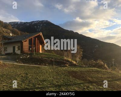 Ce cottage moderne est situé sur des collines verdoyantes et offre une vue panoramique sur les montagnes et les nuages au coucher du soleil Banque D'Images