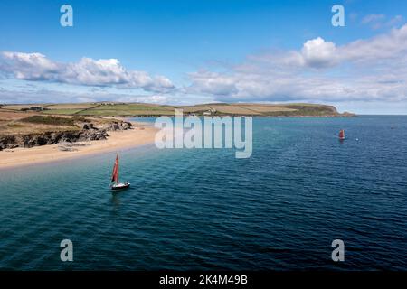 Un bateau à voile à l'ancienne avec une voile rouge flottant sur l'océan dans l'estuaire de la Camel près de Padstow dans les Cornouailles Banque D'Images