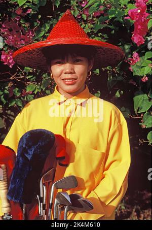 Thaïlande. Nakhon Pathom. Jardin de roses. Portrait extérieur de la femme thaïlandaise caddie avec des clubs de golf. Banque D'Images