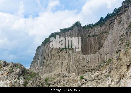 Haute falaise côtière formée par des colonnes de pierres de lave solidifiées, cap Stolbchaty sur l'île de Kunashir Banque D'Images