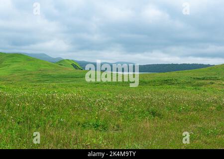 Magnifique paysage de l'île de Kunashir avec des collines herbeuses et un lac éloigné Banque D'Images