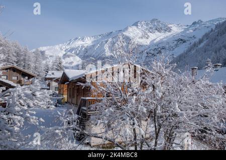 Chalets de montagne dans un petit hameau au-dessous de la crête alpine, couverts de neige fraîche dans la vallée de Chamonix en France Banque D'Images