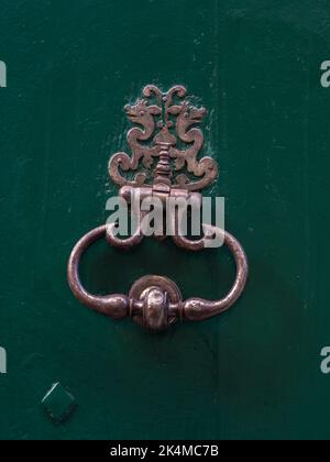 Vue rapprochée du knocker traditionnel de porte en laiton vintage isolé sur une ancienne porte en bois vert foncé, Montpellier, France Banque D'Images