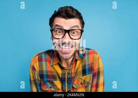 Photo d'un homme fou sans voix impressionné dans des lunettes vêtu d'une chemise à carreaux avec vue sur l'appareil photo isolé sur fond bleu Banque D'Images