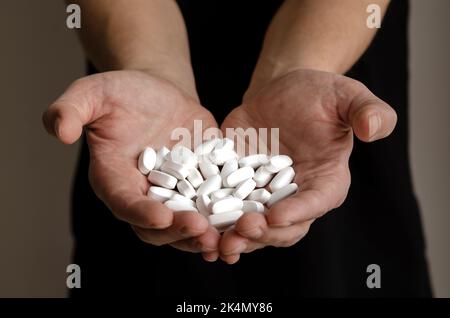 Beaucoup de pilules blanches dans les mains d'un homme adulte Banque D'Images