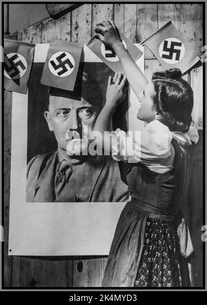 Les troupes allemandes nazies l'occupation d'une jeune fille en Tchécoslovaquie habillent des drapeaux de la croix gammée autour du portrait d'Adolf Hitler en uniforme militaire pour montrer son soutien à l'Allemagne nazie 1938 Sudètes Tchécoslovaquie Banque D'Images