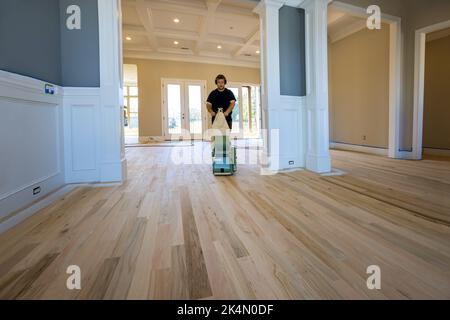 Un procédé de meulage d'un parquet en bois en utilisant une ponceuse de plancher dans une maison nouvellement construite pour s'assurer qu'il est lisse et uniforme Banque D'Images