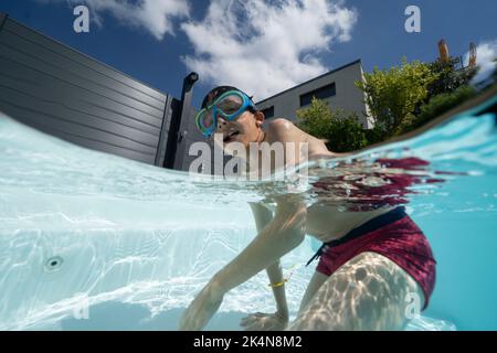Jeune garçon jouant dans une piscine Banque D'Images