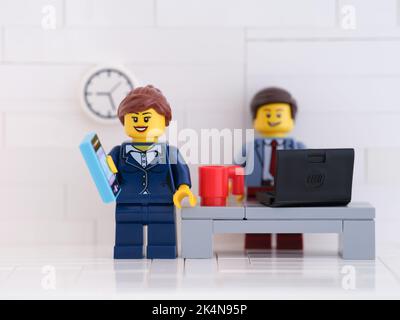 Tambov, Fédération de Russie - 01 octobre 2022 Une femme d'affaires de Lego qui se tient et utilise un smartphone dans son bureau. Banque D'Images