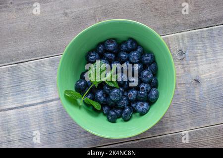 Bleuets dans un bol avec des feuilles de menthe. Banque D'Images