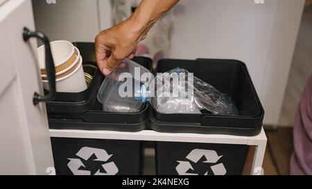 Une femme trie les déchets en jetant des bouteilles et des contenants en plastique dans des poubelles dans la cuisine. La femme au foyer prend soin de l'environnement et de l'écologie de près Banque D'Images