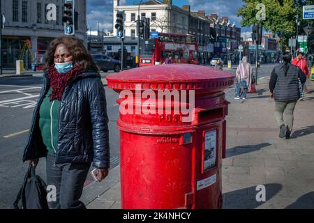 Londres, Royaume-Uni. Septembre 29 2022 . Le syndicat des travailleurs prend d'autres mesures de grève nationale. Une femme marche à côté de la boîte postale rouge traditionnelle à Lewisham, Londres, Angleterre. Banque D'Images