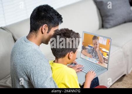 Père et fils utilisant un ordinateur portable sur le canapé dans la salle de séjour Banque D'Images