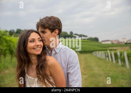 Pendant la promenade romantique dans le vignoble, le petit ami chuchote des mots à son amant et elle écoute amusé. Banque D'Images